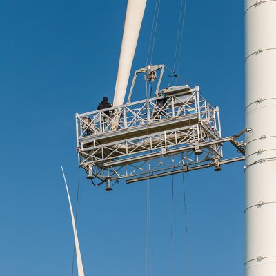 Montéři na montážní plošině provádějí revizi, nebo opravu listu rotoru větrné elektrárny (Zdroj: © Martin Bergsma / stock.adobe.com)