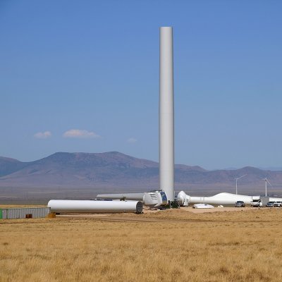 Výstavba větrné elektrárny ve fázi vztyčování ocelového tubusu. Na zemi je připravena gondola a vrtule (Zdroj: © Chris Galbraith / stock.adobe.com)