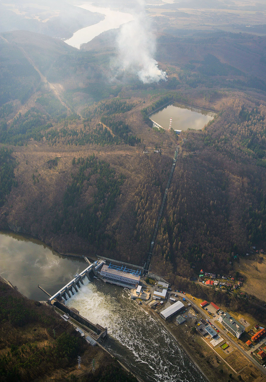 Průtočná vodní elektrárna Štěchovice v údolí Vltavy. Její součástí je i přečerpávací elektrárna. Na kopci Homole nad elektrárnou leží horní nádrž. Je vidět potrubí, které spojuje horní nádrž s elektrárnou (Zdroj: ČEZ, a. s.)